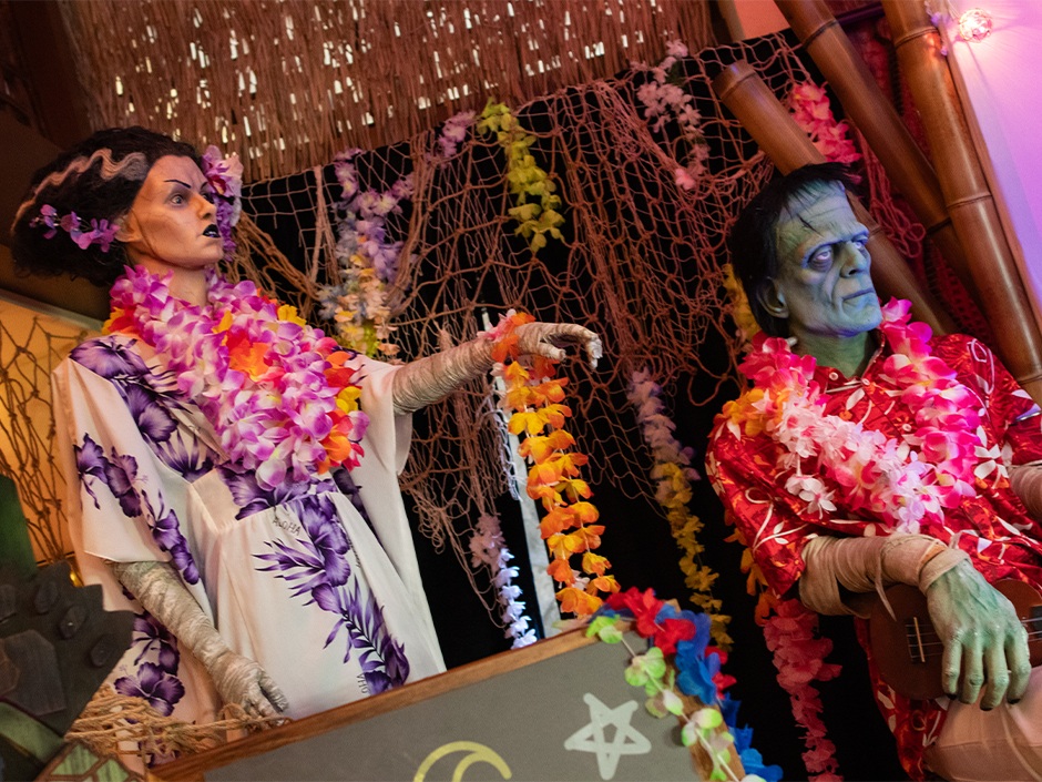 The Bride of Frankenstein and Frankenstein’s Monster wear leis at Universal Monsters Laguna Lounge