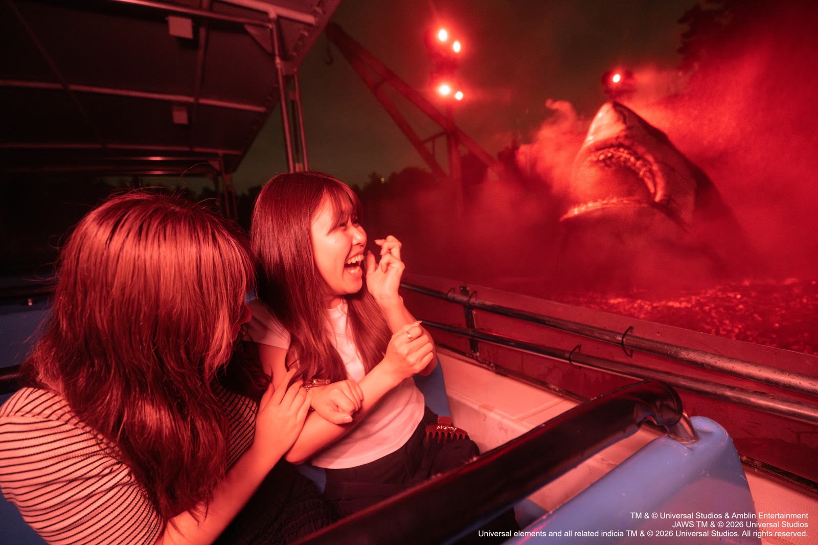 Riders face the Jaws shark under red nighttime lighting at Universal Studios Japan
