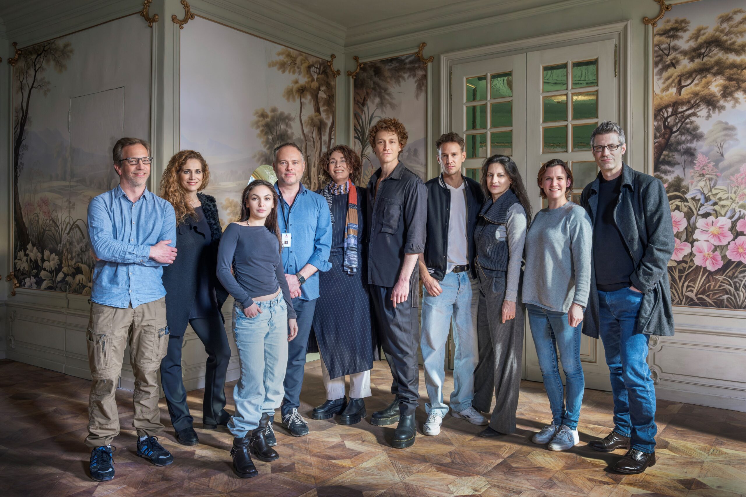 The Vienna Game cast and creative team stand together on the series set