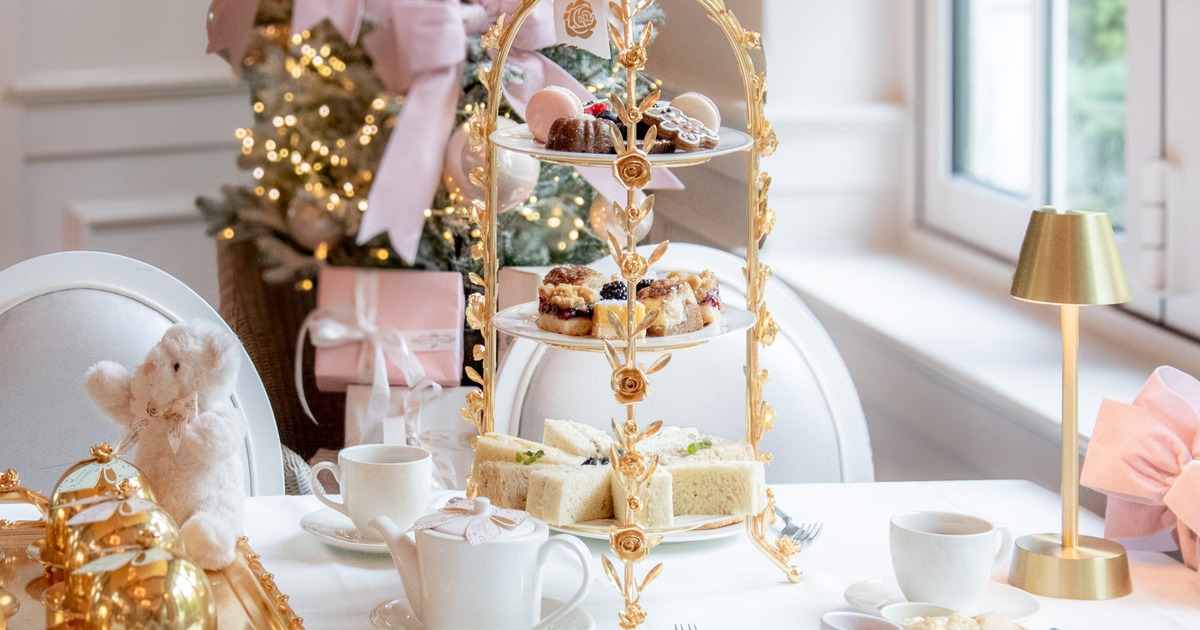 Holiday afternoon tea service with finger sandwiches, scones and desserts beside a decorated Christmas tree