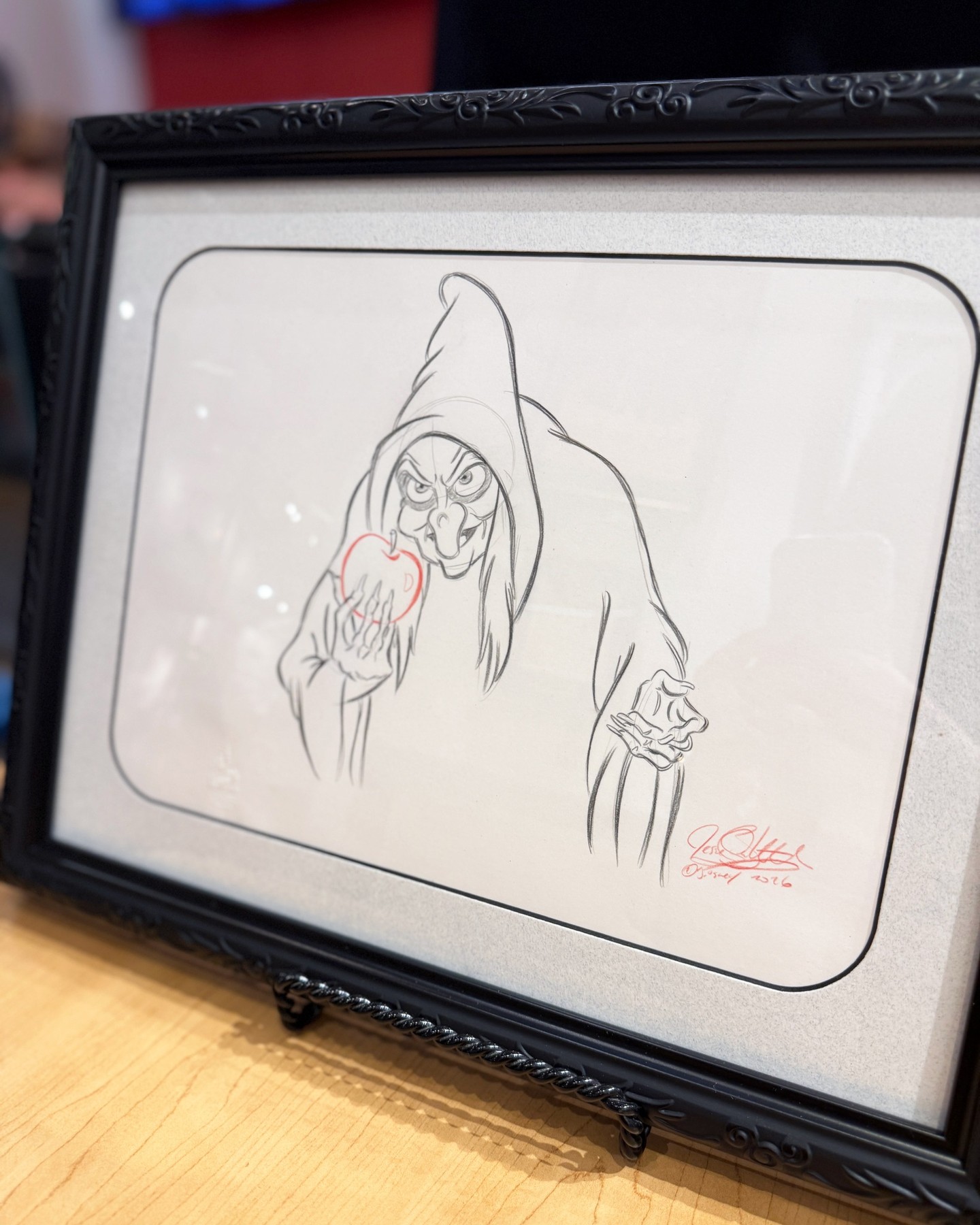 A framed hand-drawn sketch of Snow White’s Old Hag holding a red apple at The Art of Disney