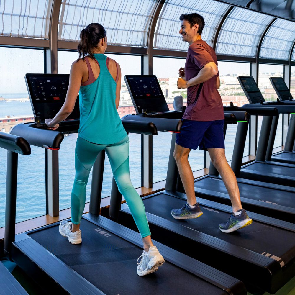 Two adults using treadmills in a Disney Cruise Line fitness center