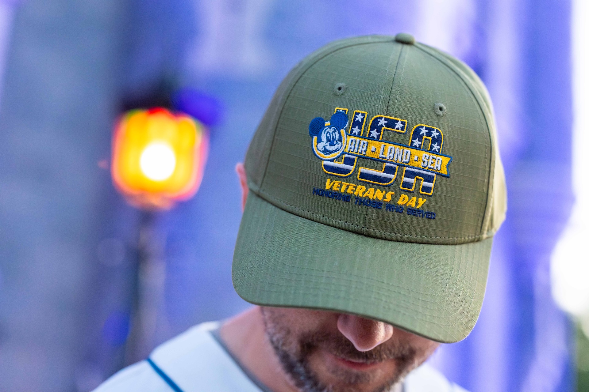 A green Disney Veterans Day baseball cap embroidered with Mickey Mouse and the words Air, Land and Sea