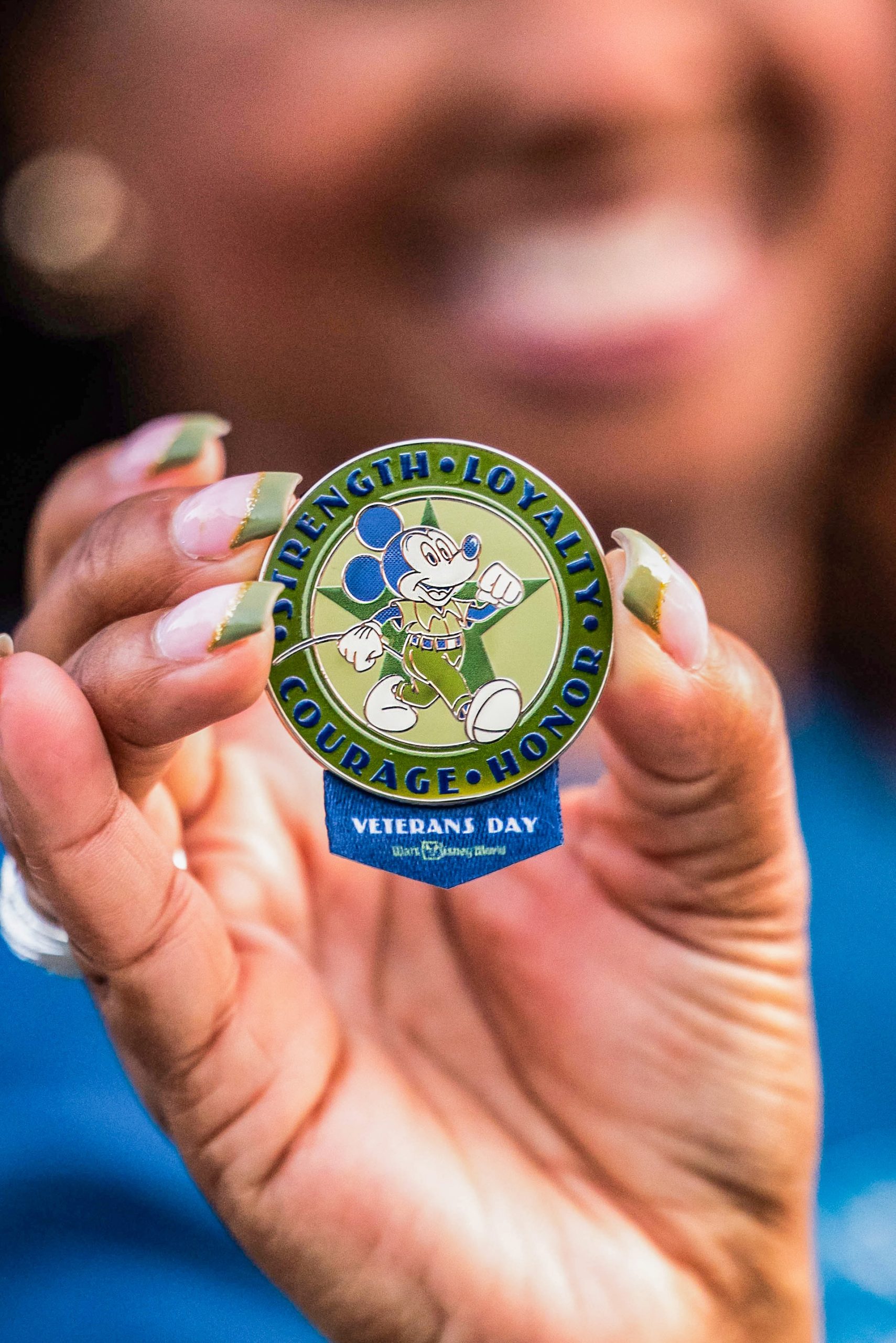 A hand holds the 2026 Disney Veterans Day commemorative pin