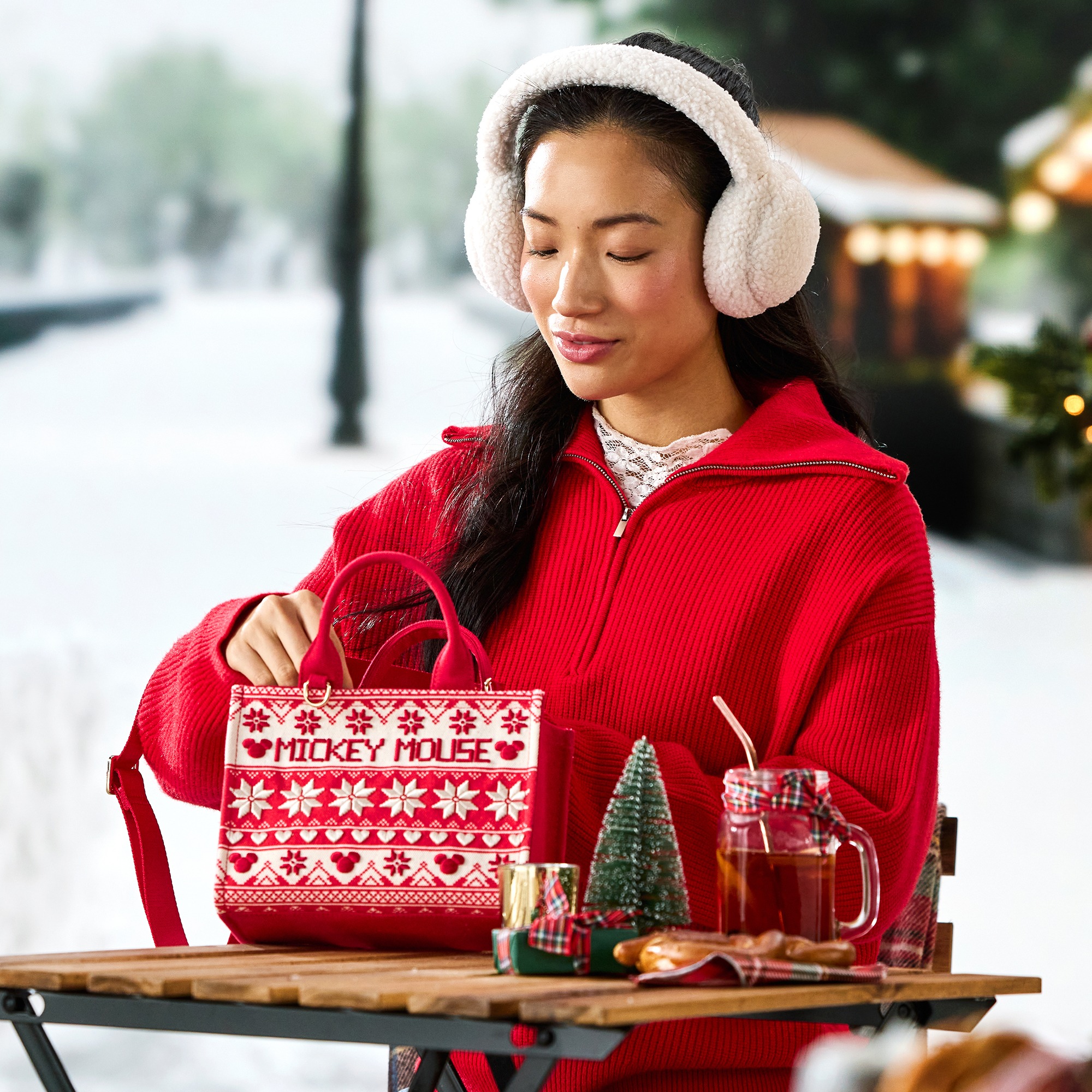 A model carries the red Mickey Mouse Fair Isle mini tote in a holiday setting