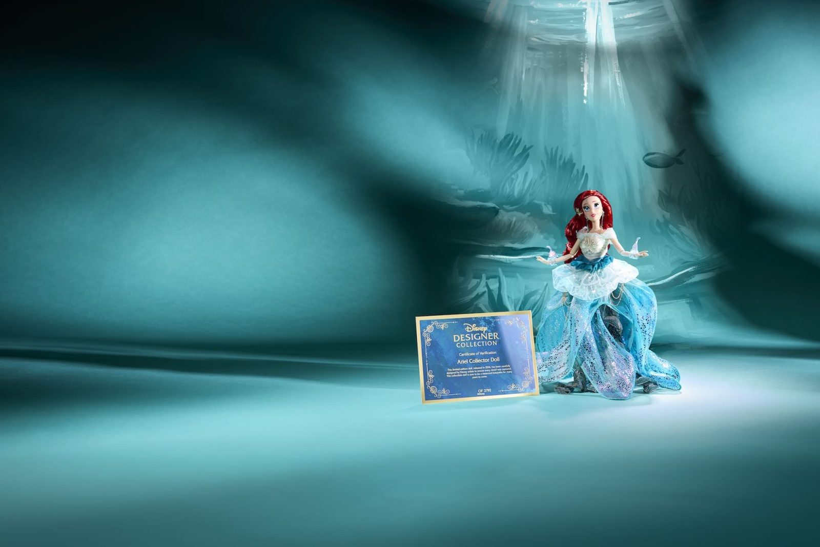 Ariel Designer Doll posed beneath a spotlight beside a display card