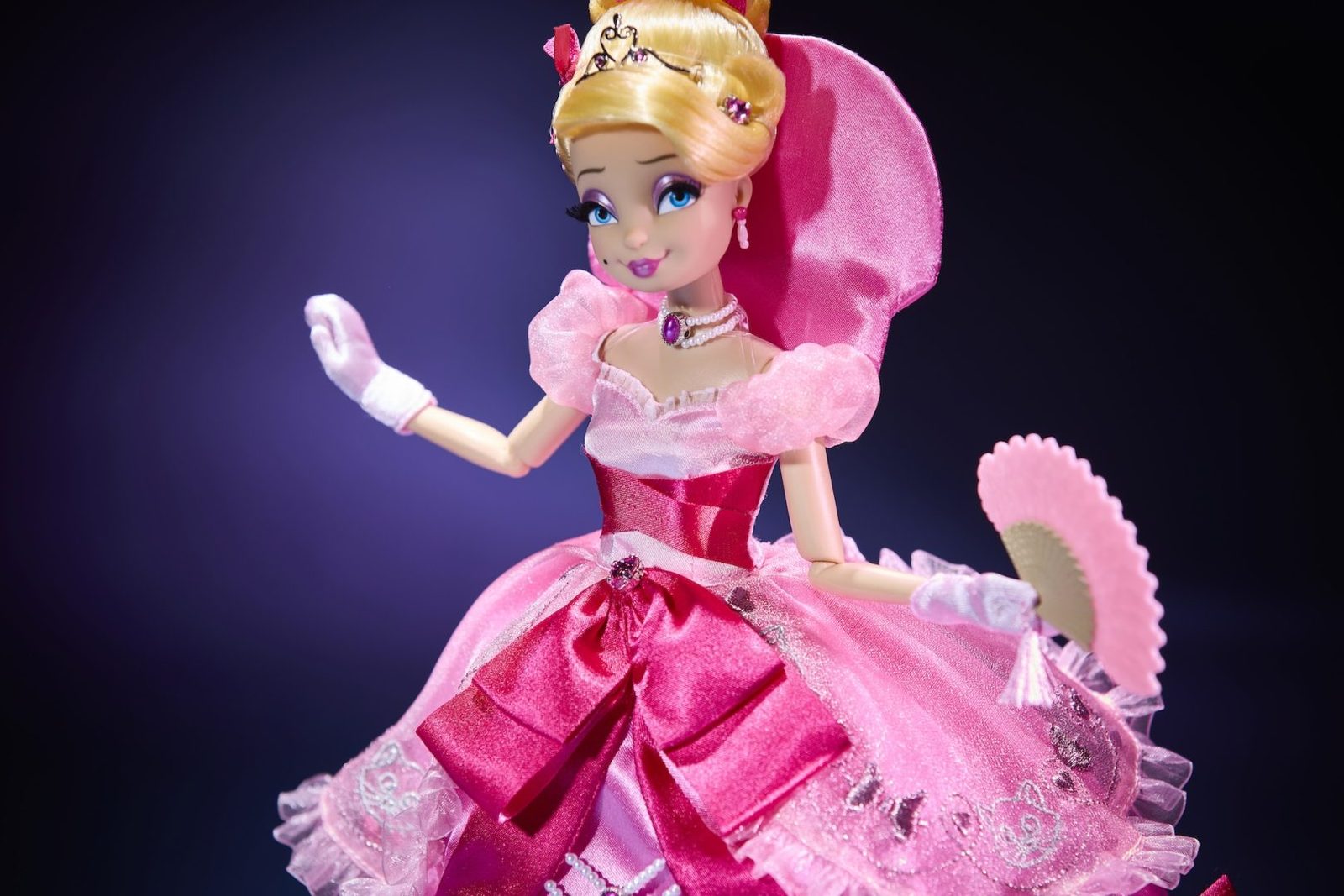 Lottie Designer Doll holding a fan with a pink bow in her hair