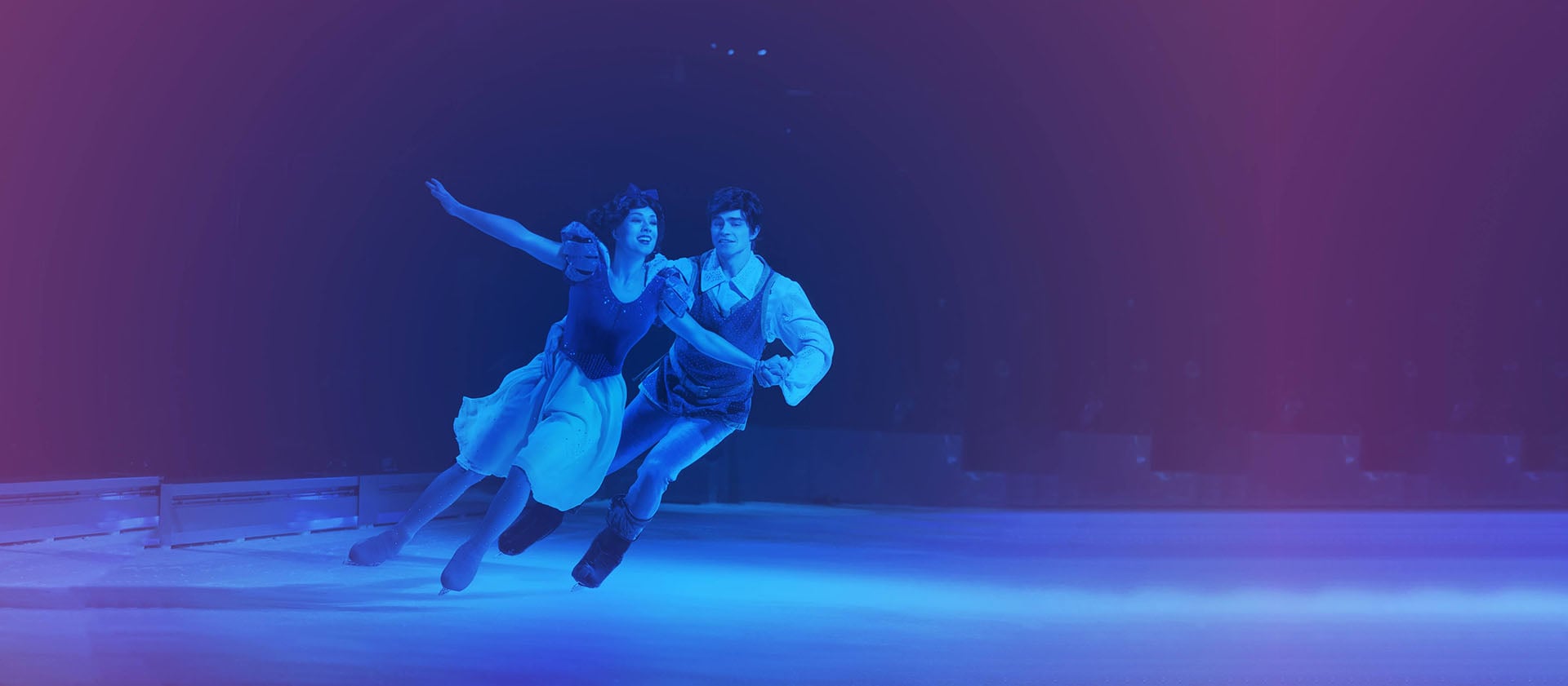 Disney On Ice skaters perform under blue and purple lights