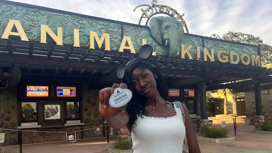 Oneiya Neymour holds her Animal Kingdom cast member name tag outside the park entrance