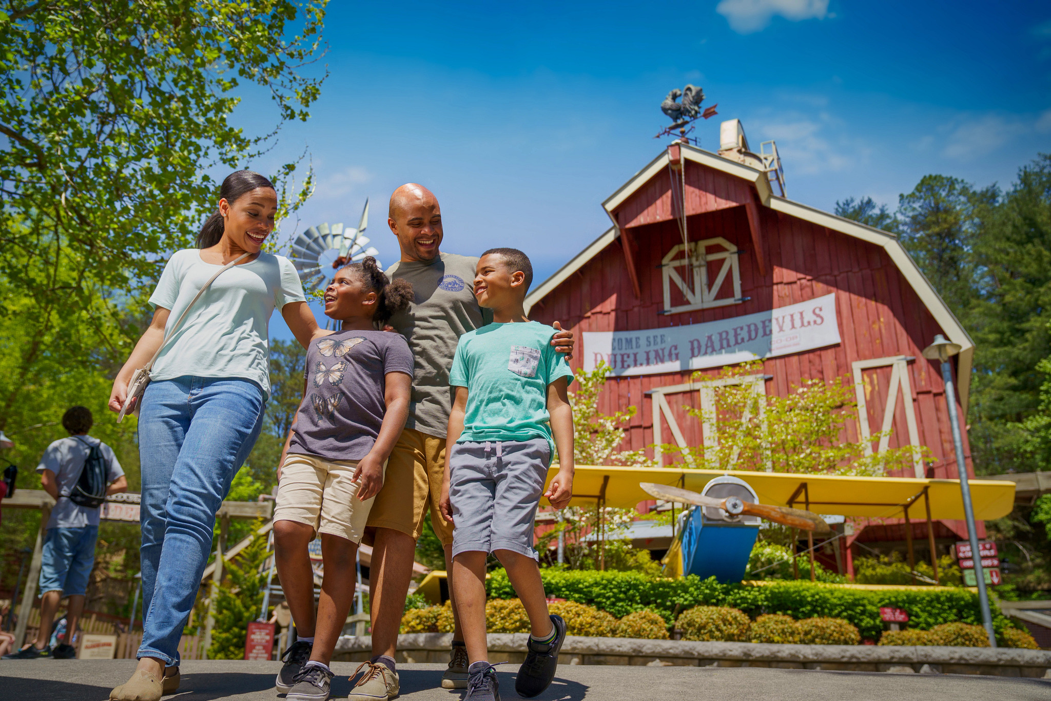 A family of four walks through Dollywood near the Dueling Daredevils attraction