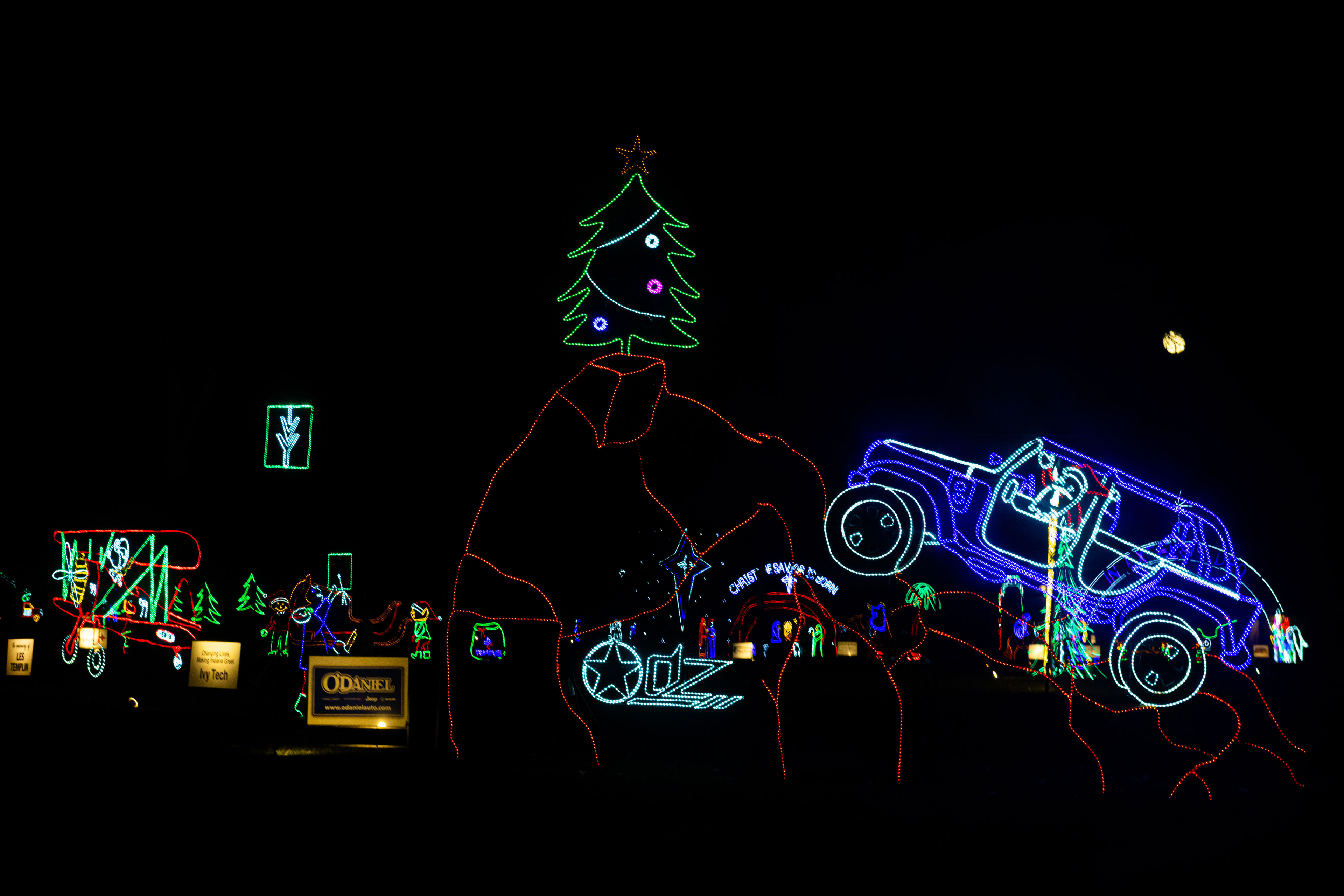 A Jeep passes a glowing Christmas tree and holiday light displays at Fantasy of Lights in Fort Wayne