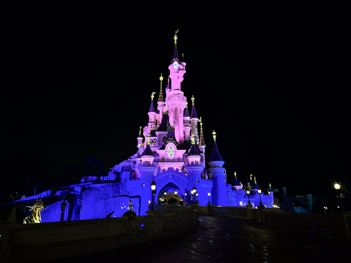 Sleeping Beauty Castle at Disneyland Paris illuminated in pink and blue at night