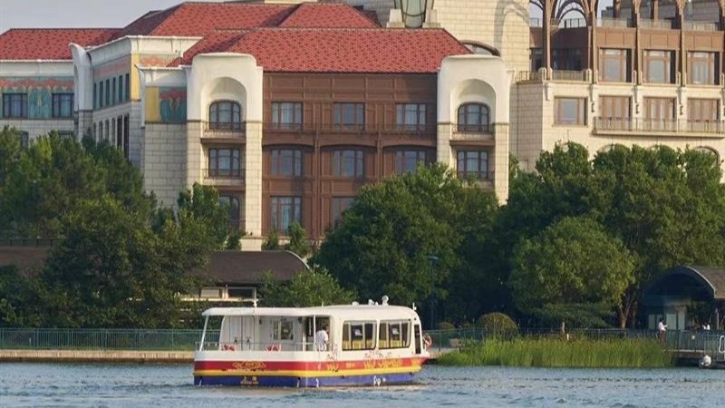 A Wishing Star Ferry boat crosses the lake in front of Shanghai Disneyland Hotel