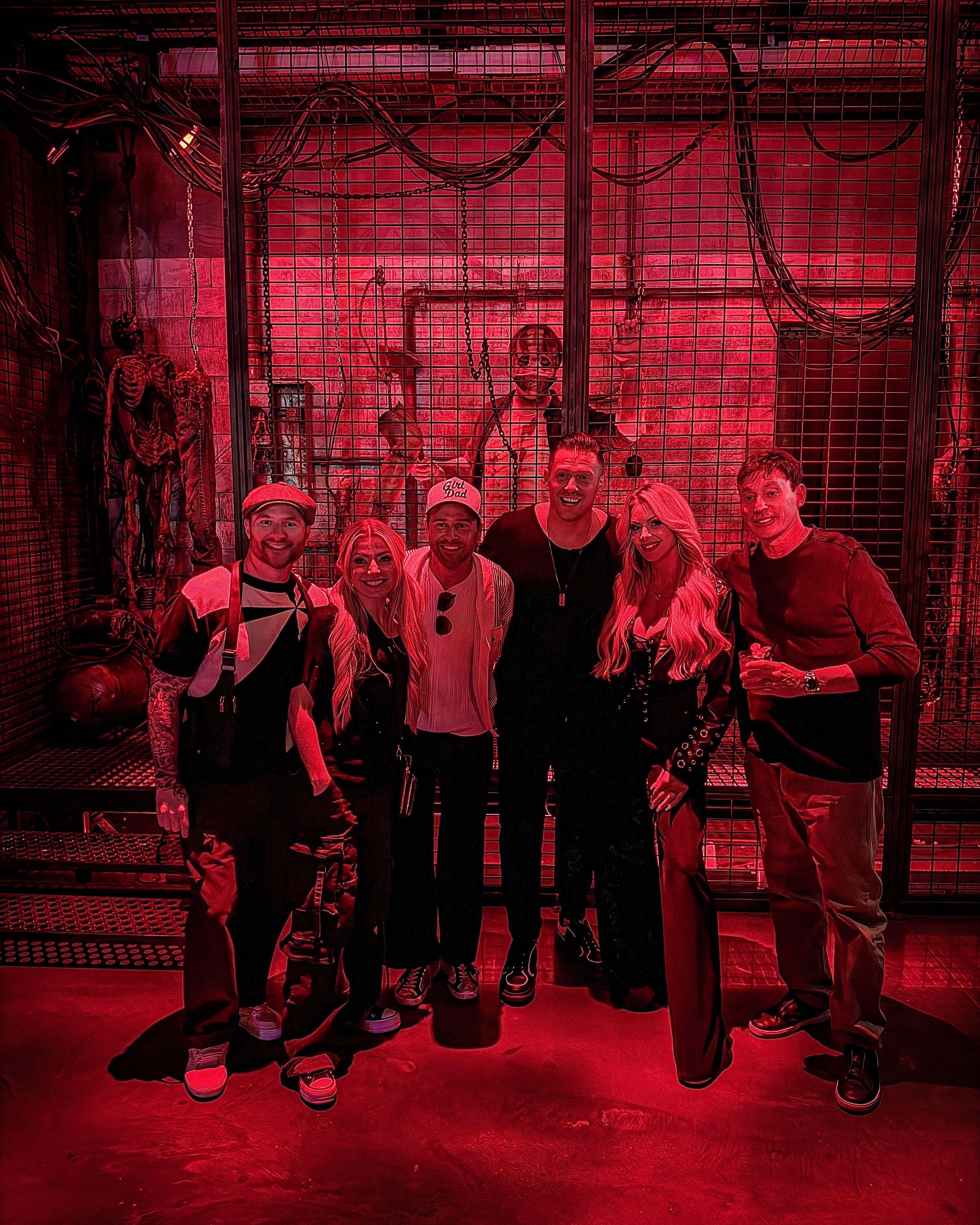 The Miz and guests react beside costumed performers in a red-lit cage at Universal Horror Unleashed