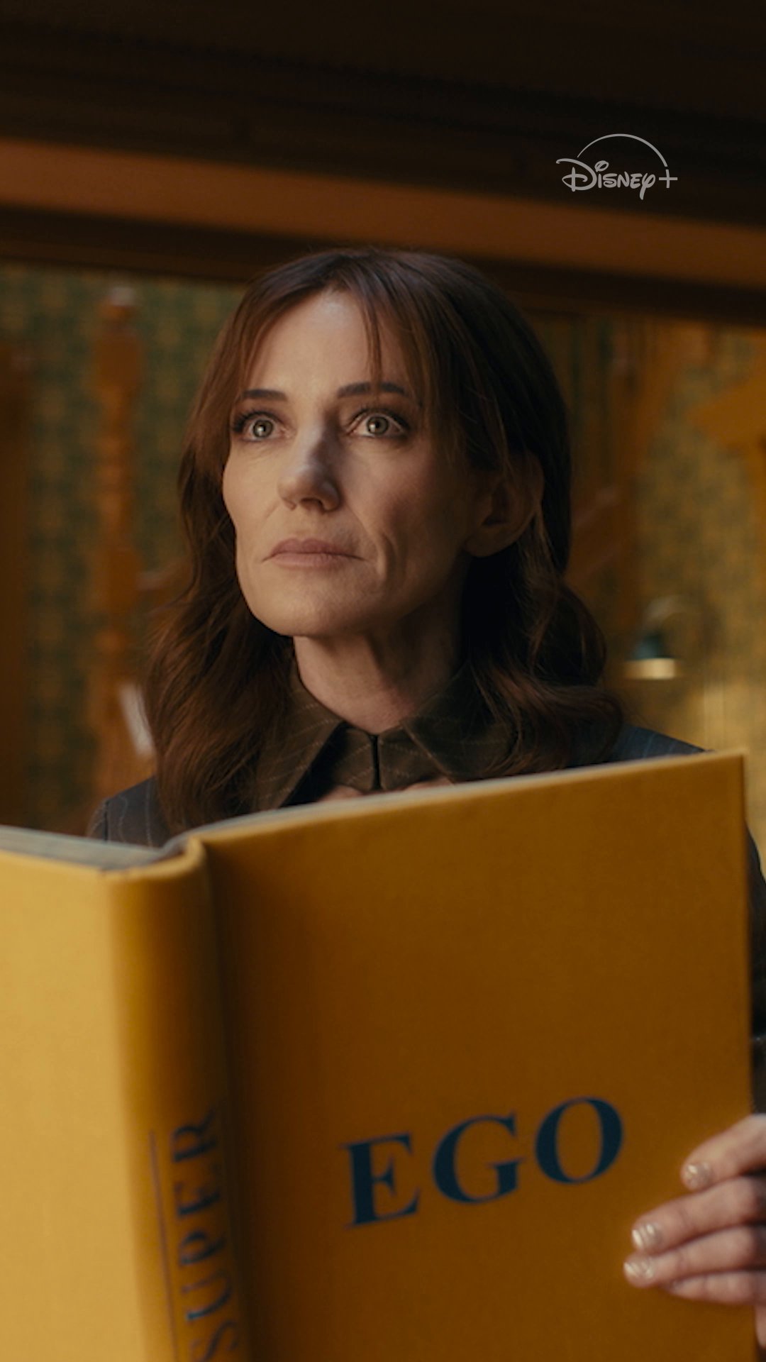 A woman holds an open yellow book in the VisionQuest Disney+ promo
