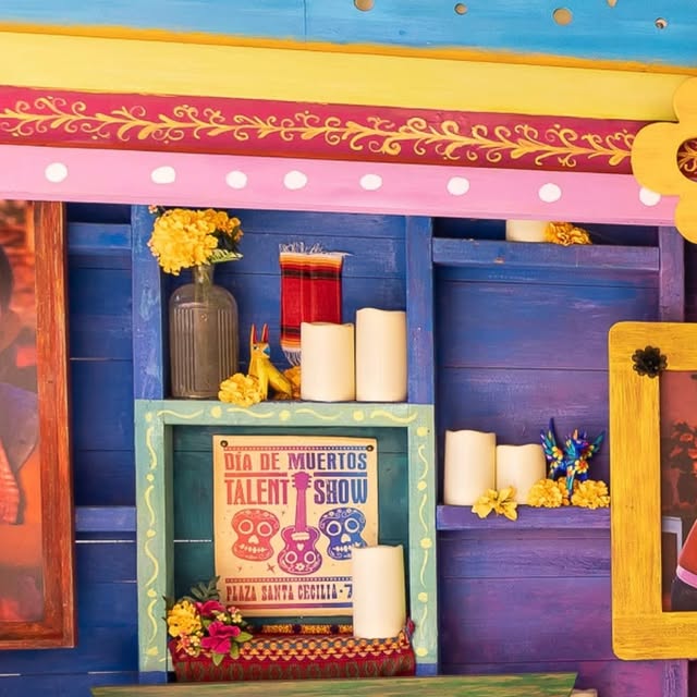 Plaza de la Familia display with Coco family portraits, marigolds and a Día de Muertos Talent Show poster