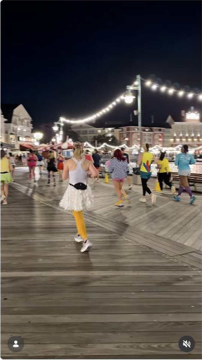 Runners move through a brightly lit boardwalk setting during the Disney Wine & Dine 10K