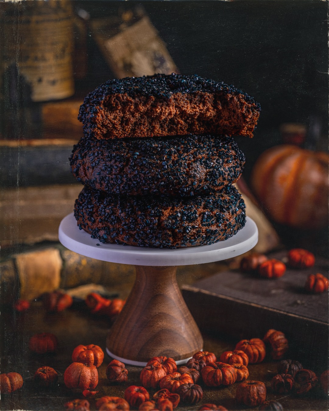 Three dark chocolate Black Cat Cookies stacked on a cake stand