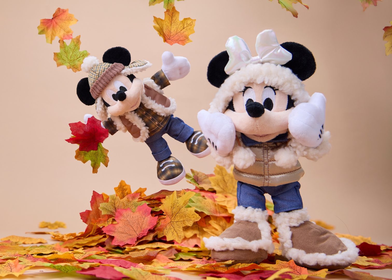 Mickey and Minnie winter plush pose among autumn leaves