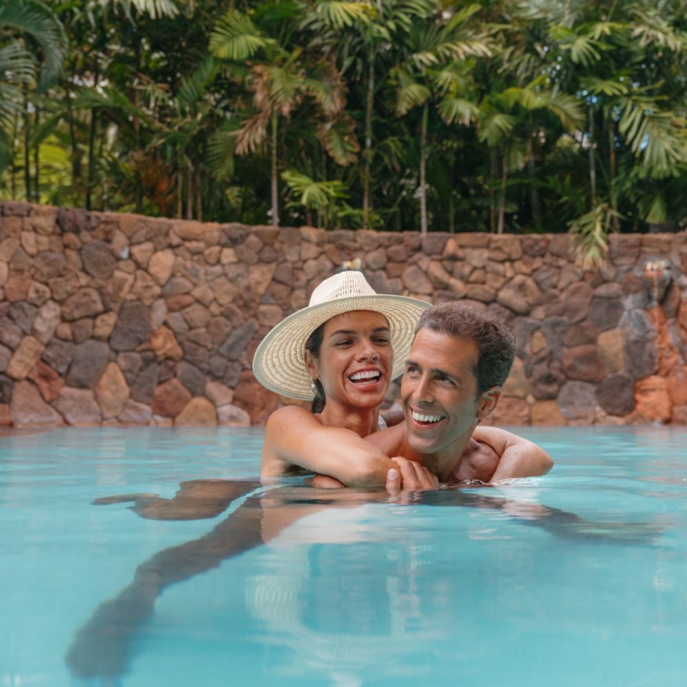 A couple relaxing in Wailana Pool at Aulani Resort