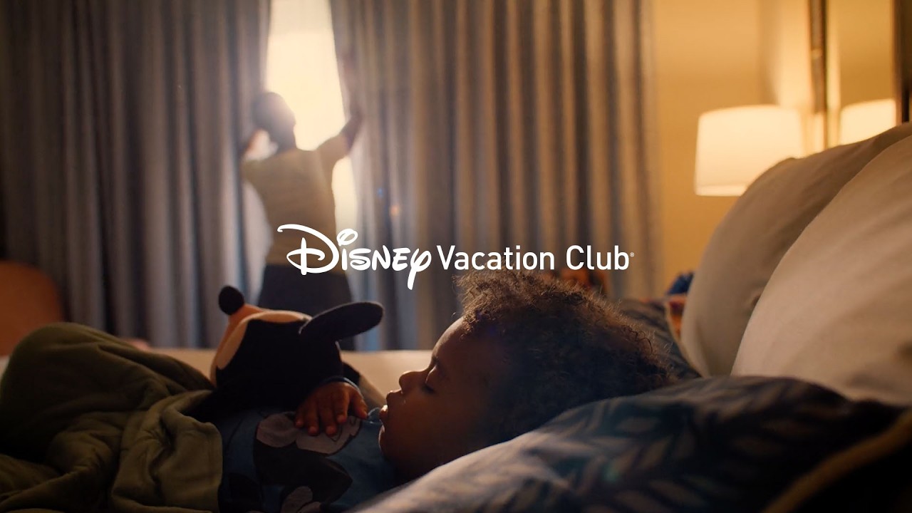 A child resting beside a Mickey Mouse plush toy in Disney Vacation Club’s campaign video