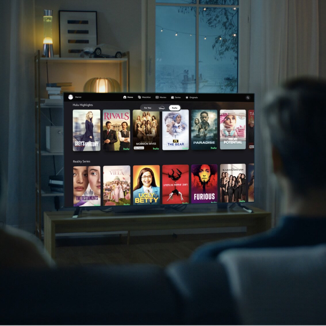 A television displays a streaming home screen while two viewers watch