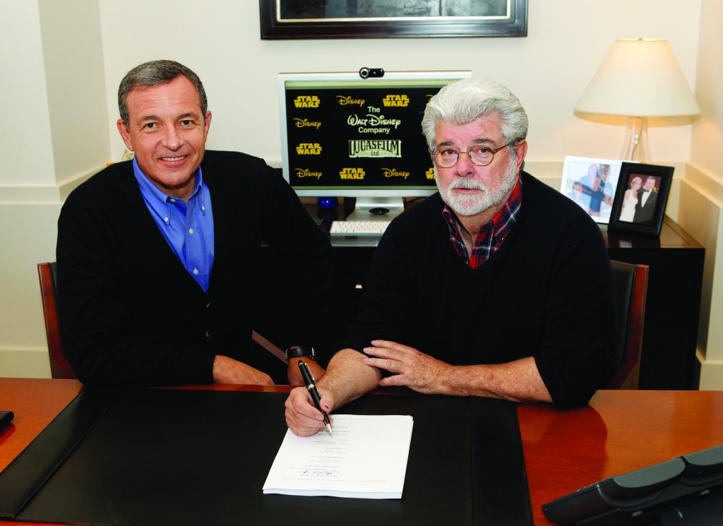 Bob Iger and George Lucas sign an agreement at a desk