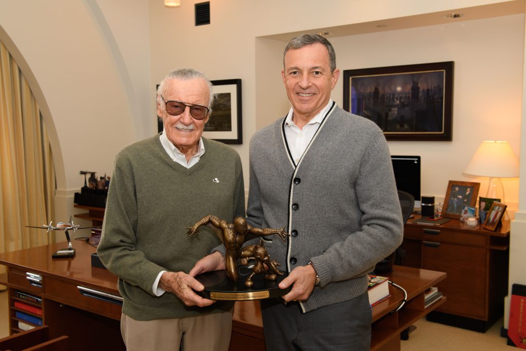 Stan Lee and Bob Iger hold a Spider-Man figure in an office