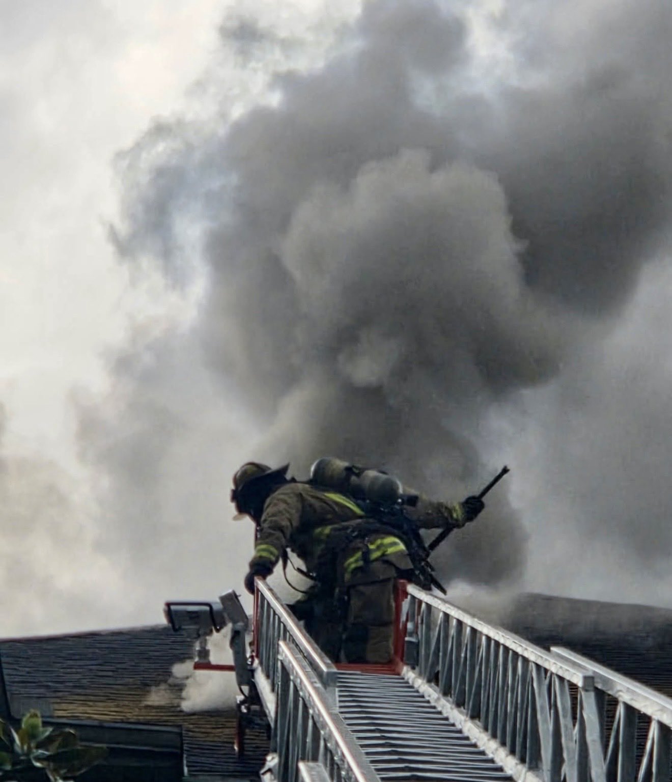 Orange County Fire Rescue firefighter on a ladder near smoke at Buena Vista Place Apartments