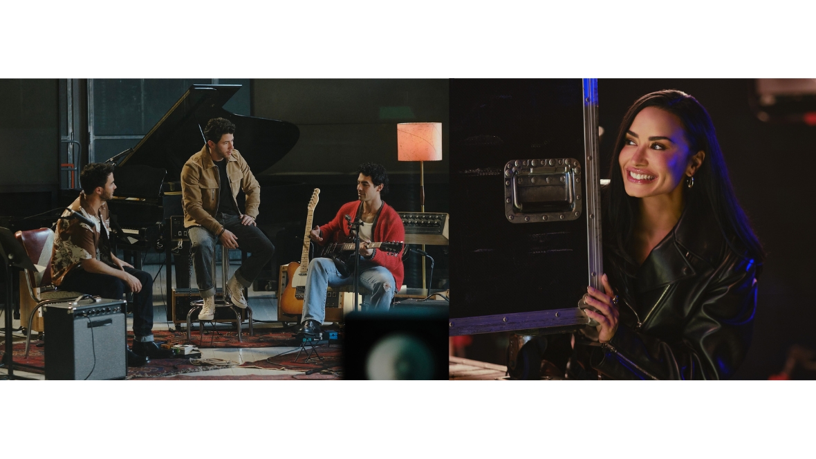 Connect 3 rehearses while Mitchie Torres peeks around a road case in Camp Rock 3