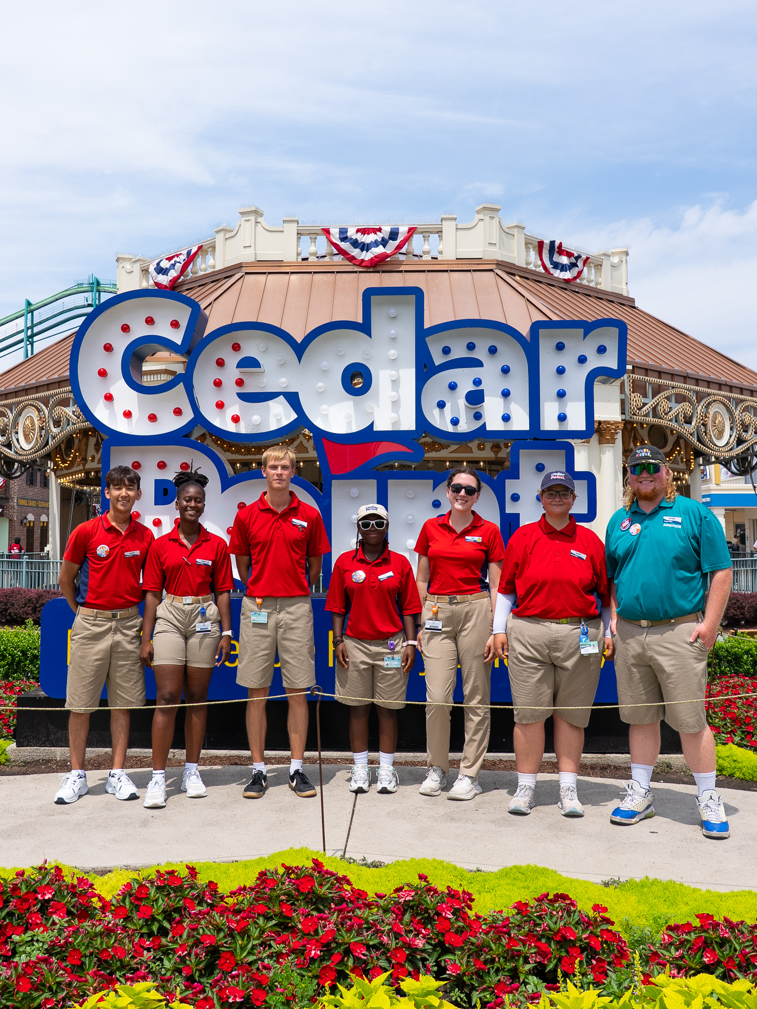 Seven Cedar Point ride operations team members in front of the Cedar Point sign