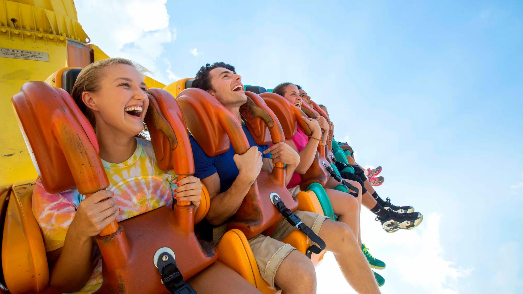 Riders secured in orange over-the-shoulder restraints on a Cedar Point pendulum ride