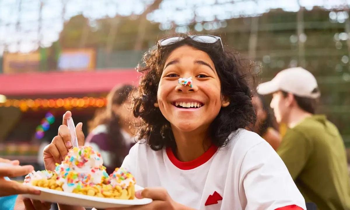 A Cedar Point guest smiles with funnel cake cream on her nose