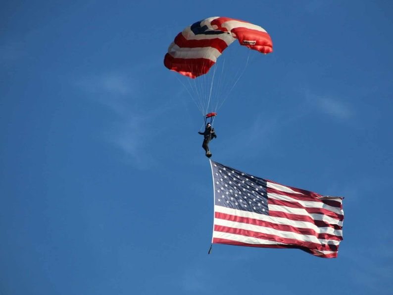 A skydiver flies above Cedar Point with smoke trailing behind