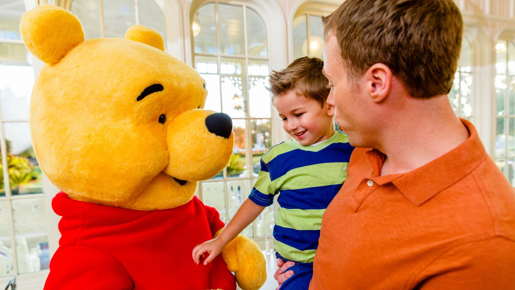 Winnie the Pooh meets a family inside The Crystal Palace at Magic Kingdom