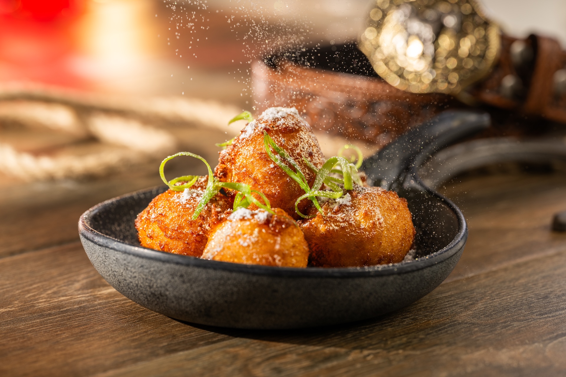 Sweet golden corn fritters topped with green onion and powdered sugar
