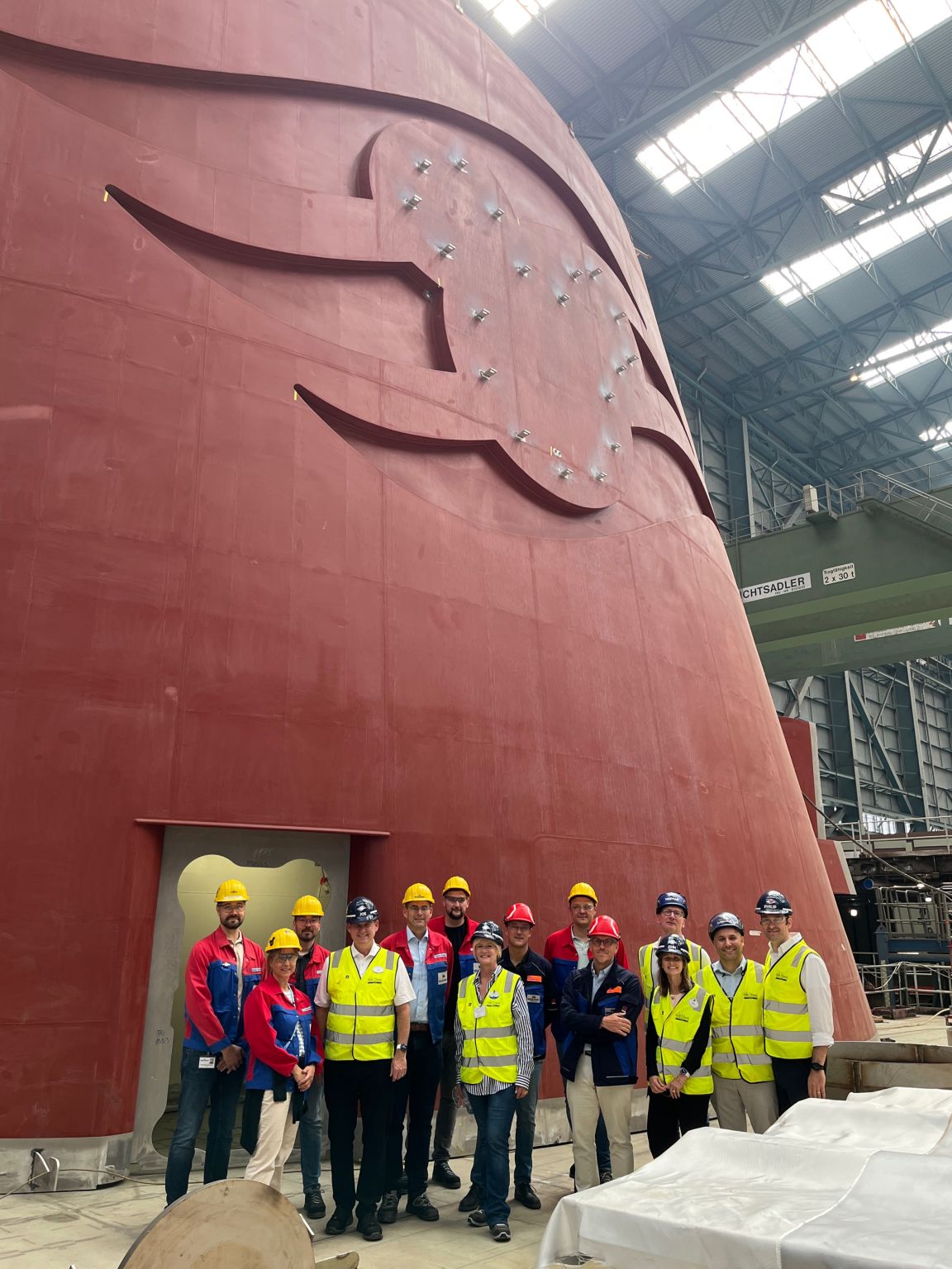 Disney Cruise Line and Imagineering team members standing beneath the unfinished Disney Believe funnel