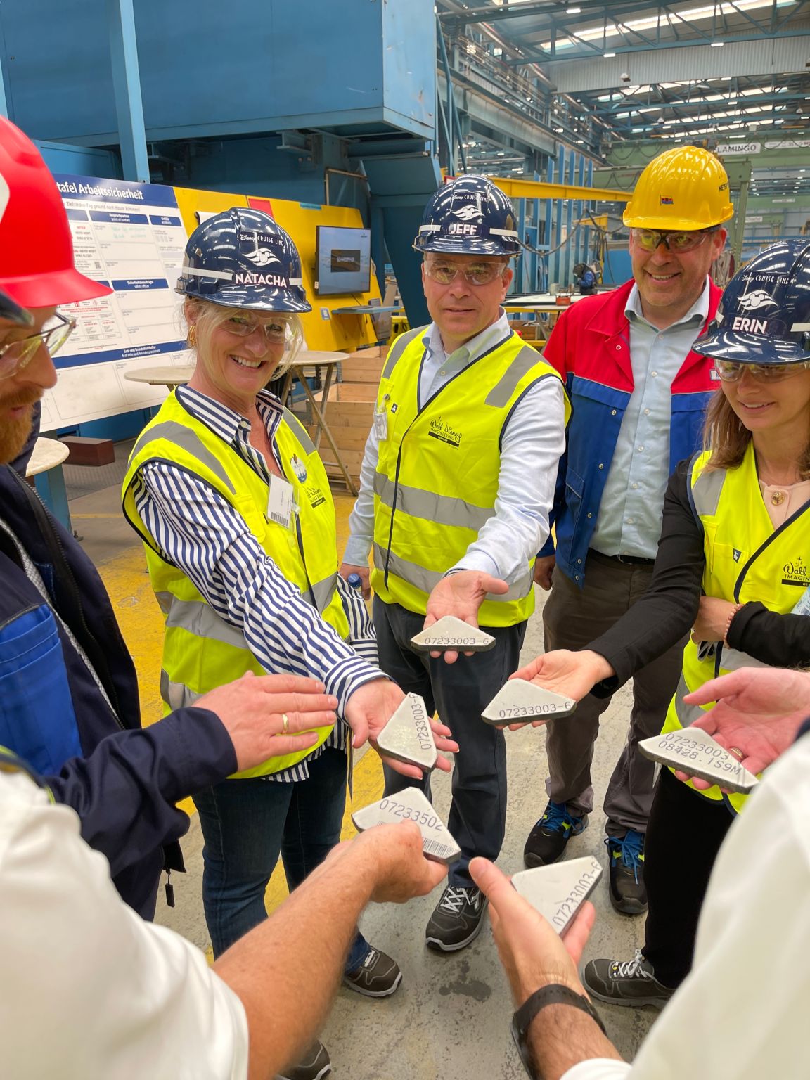 Disney Cruise Line and Imagineering team members holding stamped pieces of Disney Believe ship steel