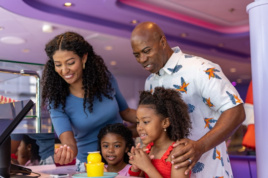A family making a purchase at a sweets counter aboard a Disney cruise ship