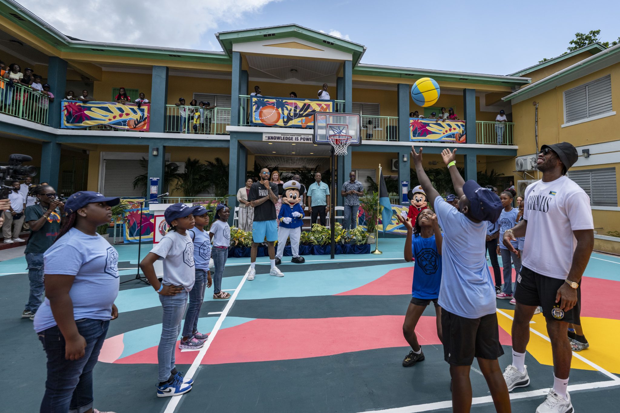 Students play basketball with Mickey Mouse and Buddy Hield at Woodcock Primary School