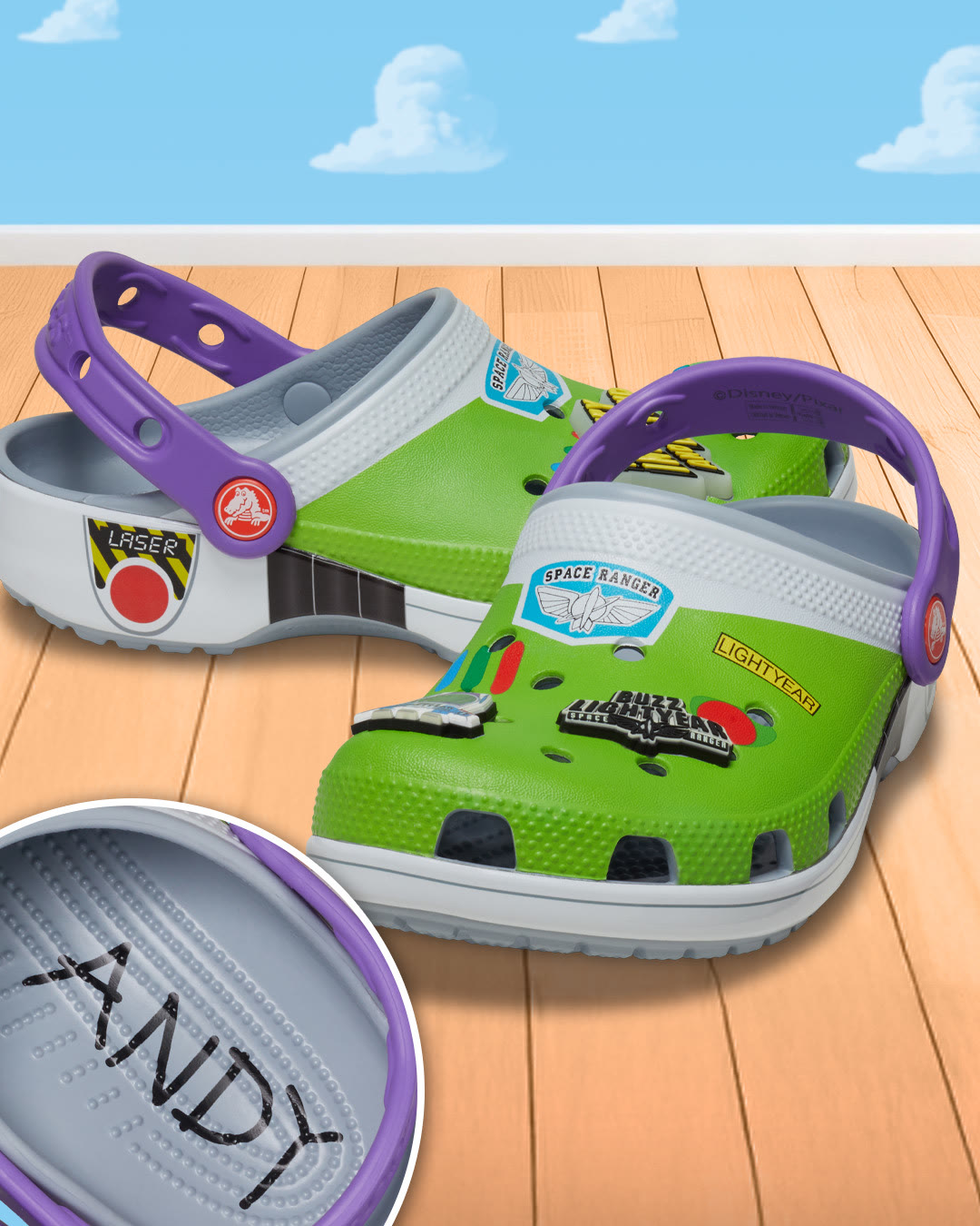Official Disney Store photo of Buzz Lightyear Toy Story Crocs with green Space Ranger graphics, purple straps, Jibbitz charms, and Andy signature