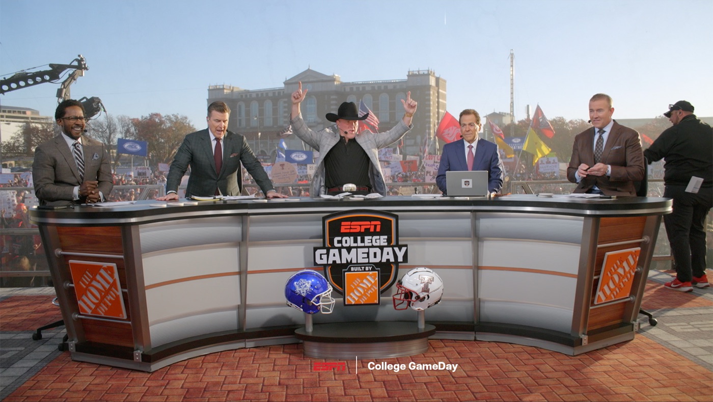 College GameDay hosts sit behind the ESPN desk