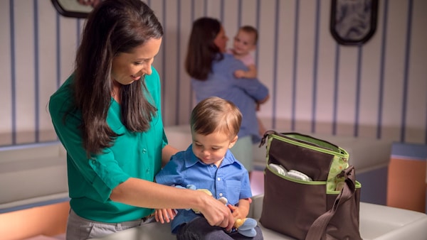 A parent helps a toddler at a changing table in the Magic Kingdom Baby Care Center.