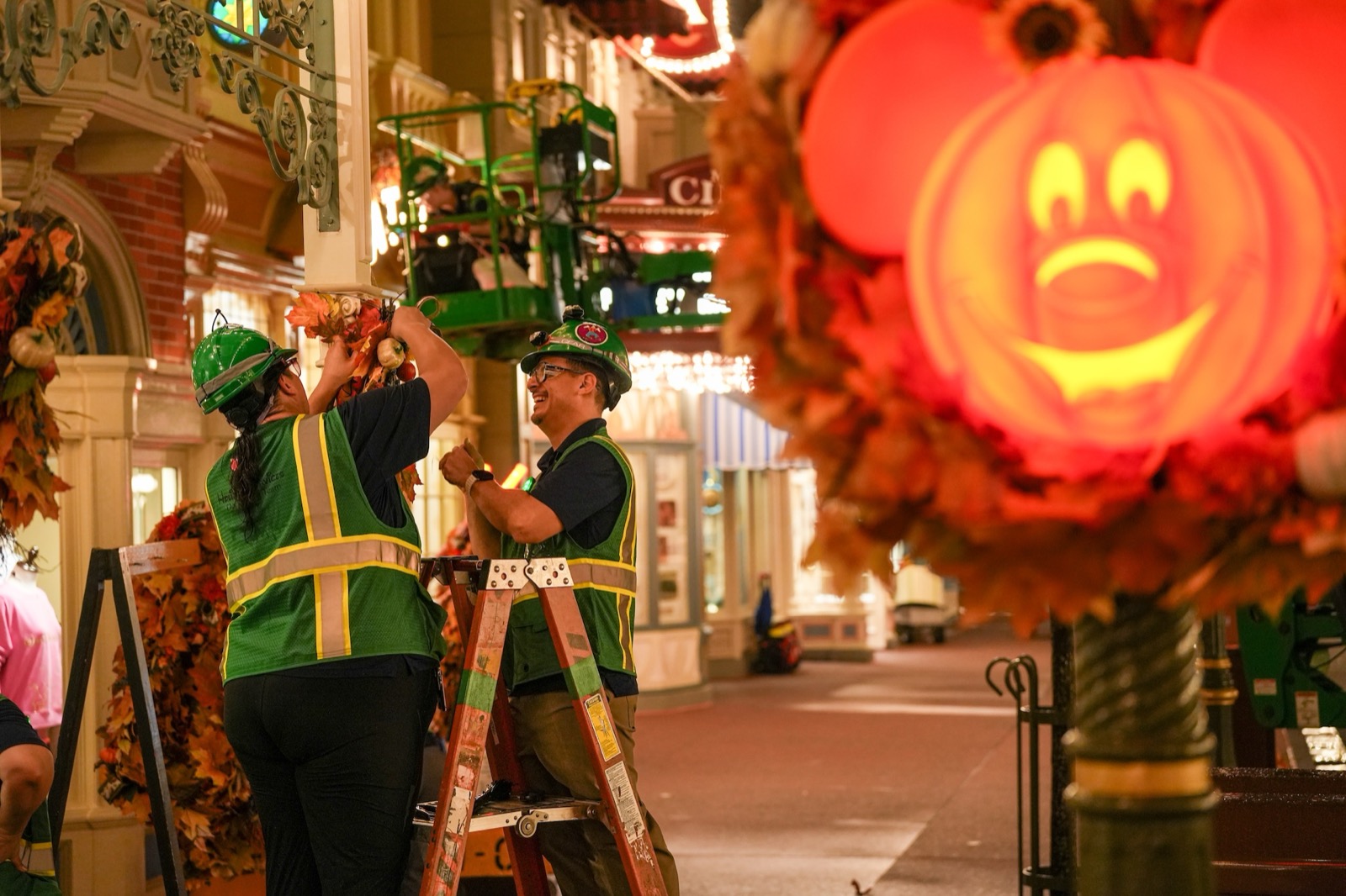 Disney Holiday Services cast members install a Mickey pumpkin wreath on Main Street U.S.A.