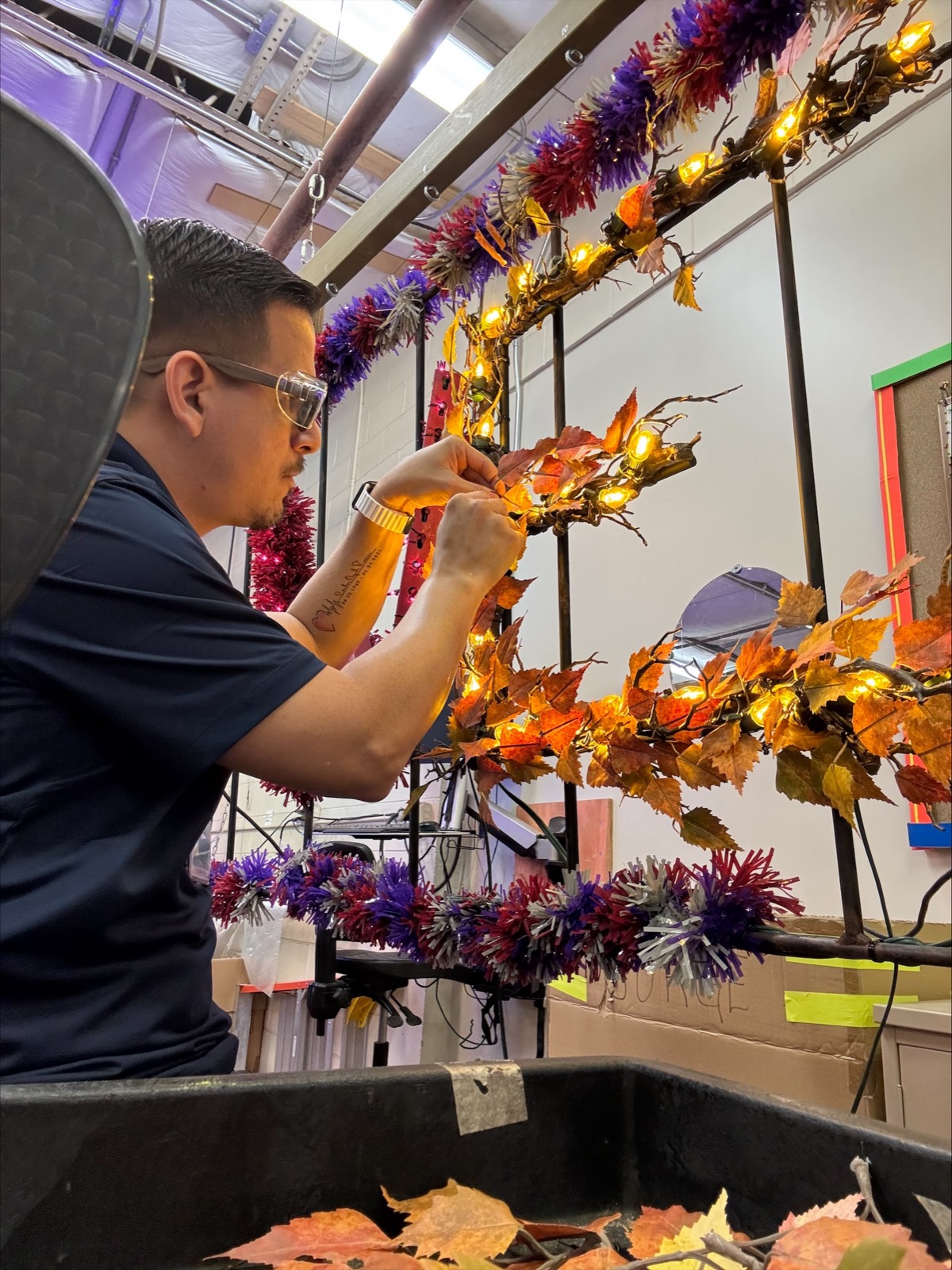 A Disney Holiday Services cast member assembles illuminated autumn garland in the workshop