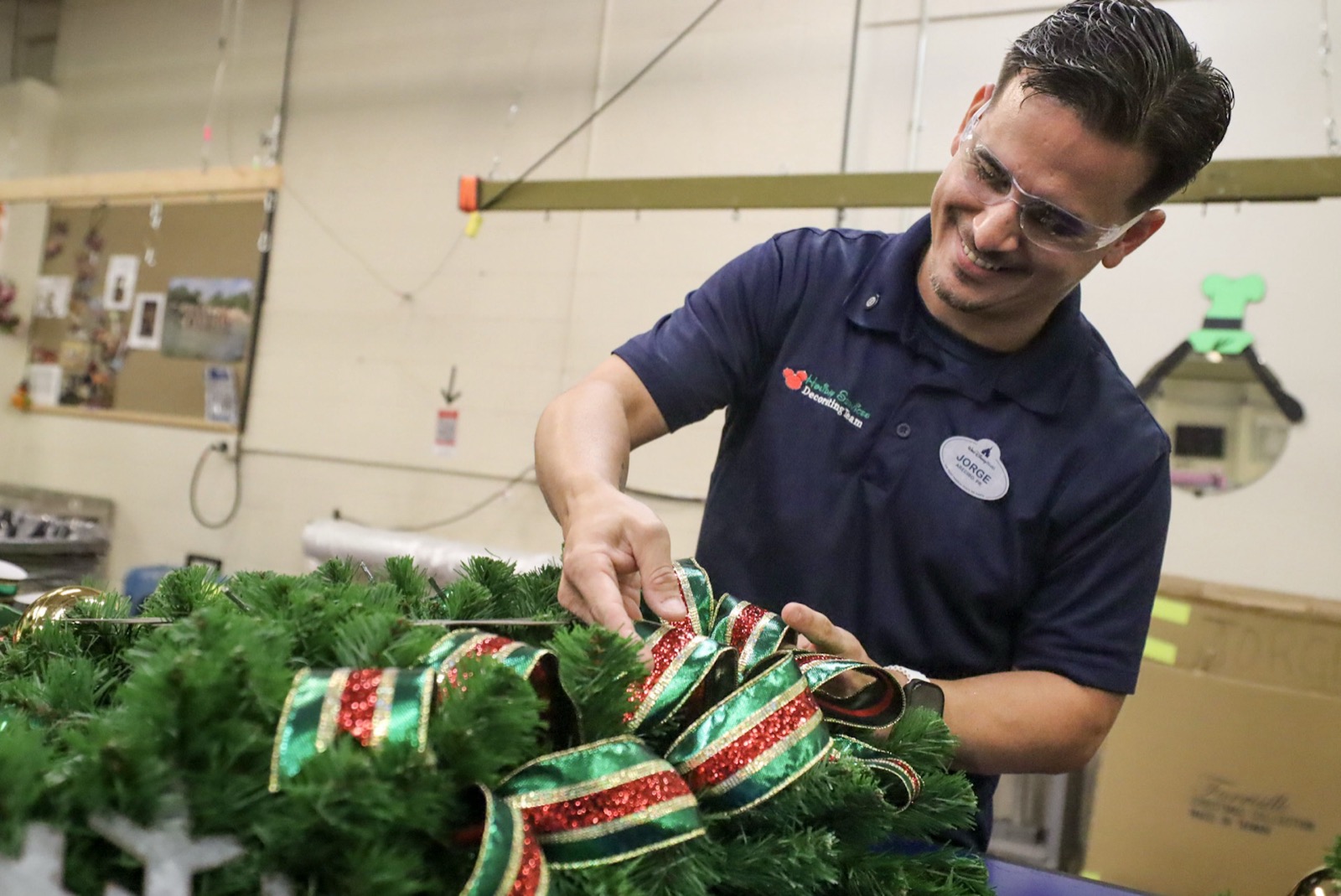 A Disney Holiday Services cast member works on a holiday wreath in the workshop