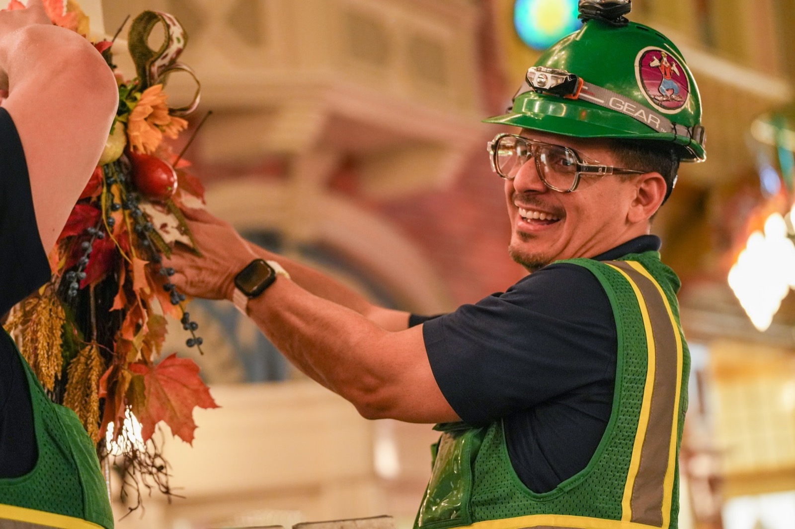 A Disney Holiday Services cast member adds autumn foliage to Halloween décor
