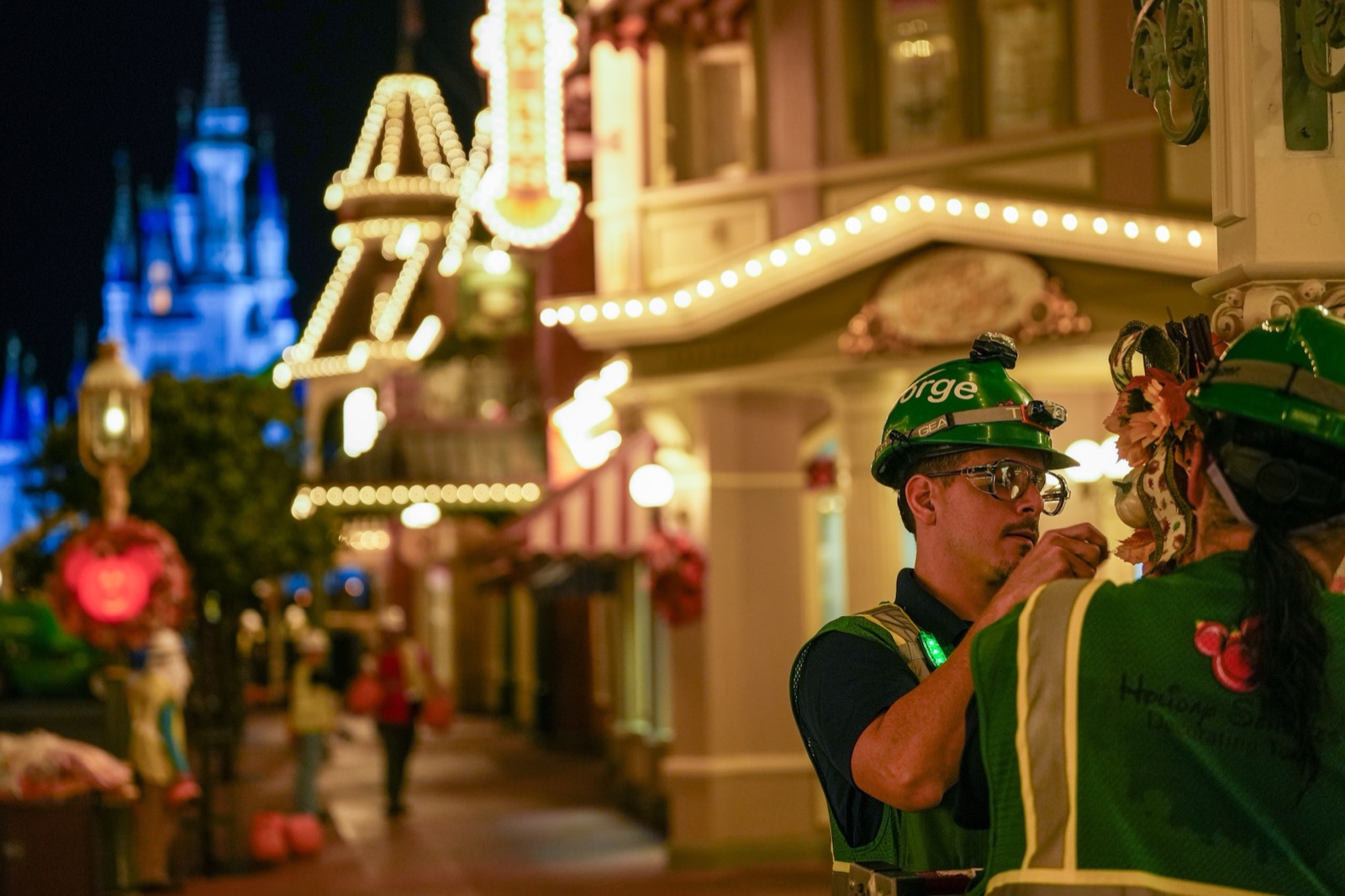 Disney Holiday Services cast members work on Halloween decorations with Cinderella Castle in the background