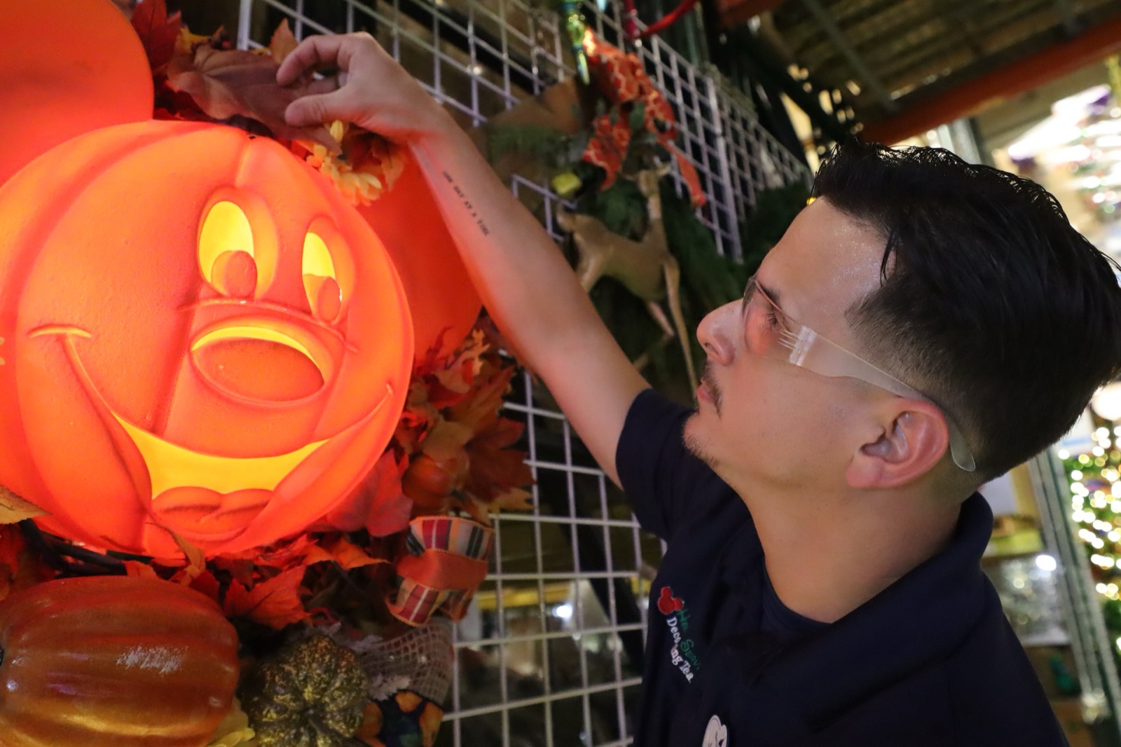 A Disney Holiday Services cast member installs a glowing Halloween pumpkin display at Walt Disney World