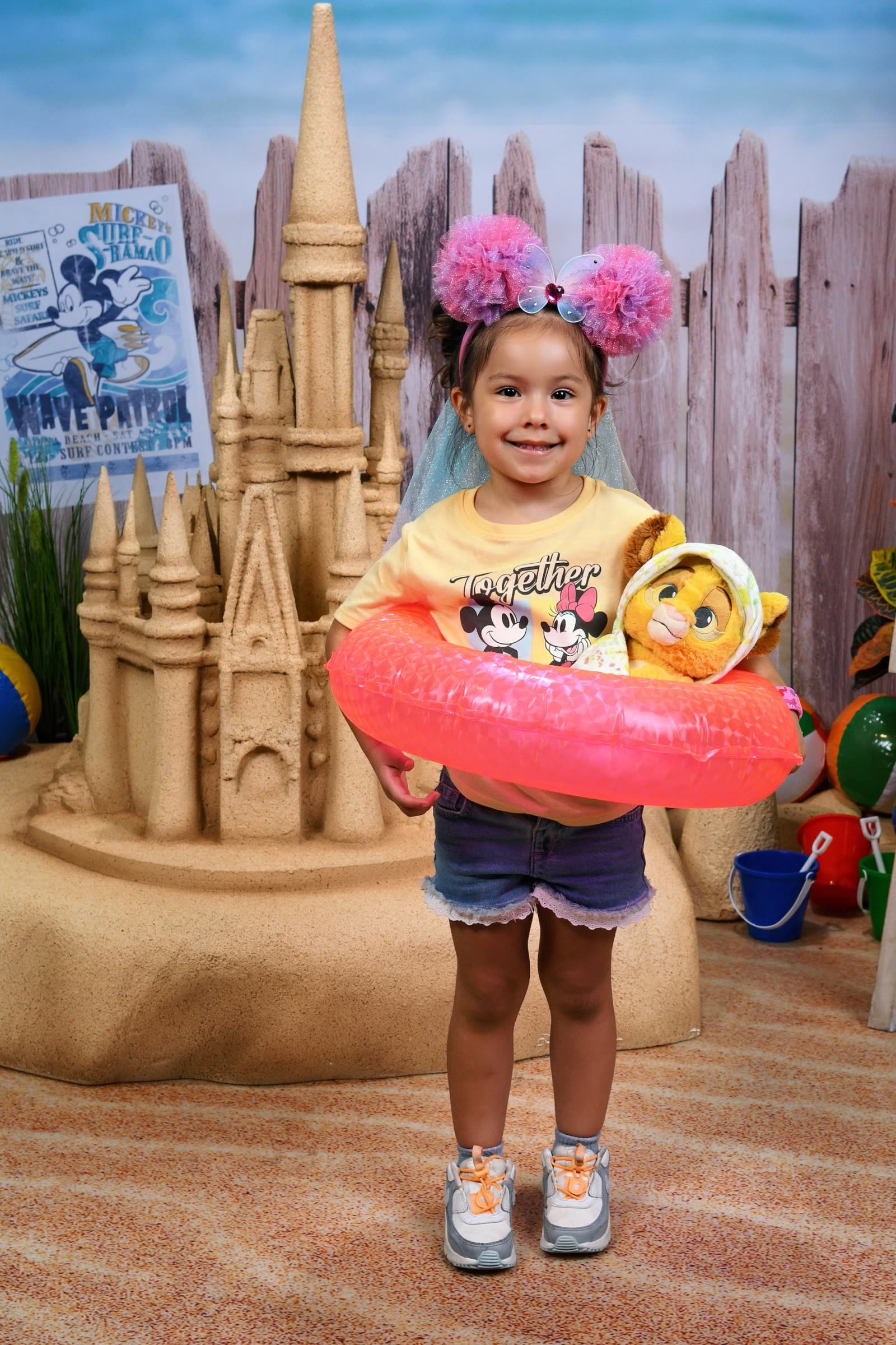 A child poses with a sandcastle prop during a Disney PhotoPass portrait session